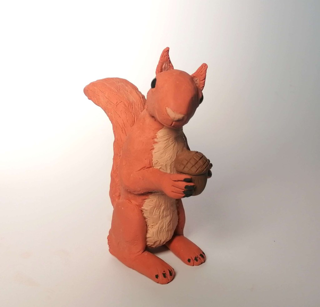 A squirrel holding a nut made out of clay